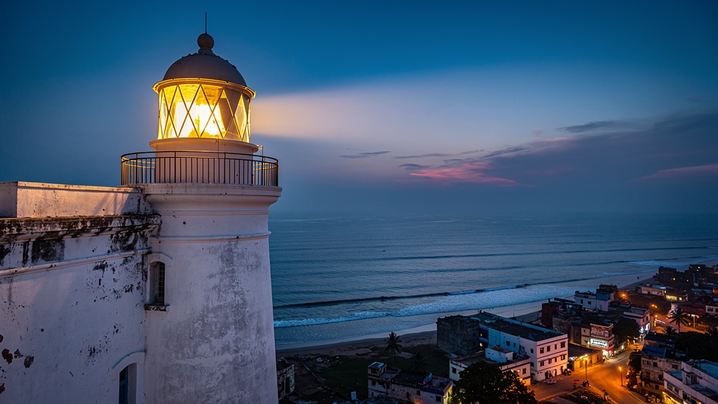 White lighthouse tower of Diu Fort against a deep blue evening sky